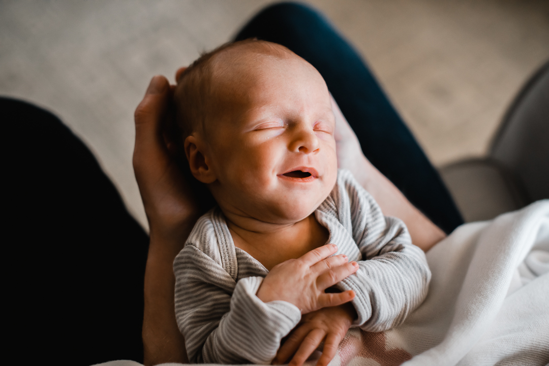 Newborn baby smiles during in-home newborn lifestyle photography session with Melissa Lindquist Photography in Omaha.